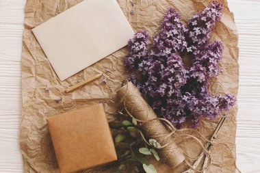 Şık bir kart, güzel leylak çiçekleri, hediye, antika makas, kırsal arka planda kalem ve sicim, üst manzara. Kırsal yaşam. Tebrik kartı şablonu, metin için boşluk. Anneler günün kutlu olsun..