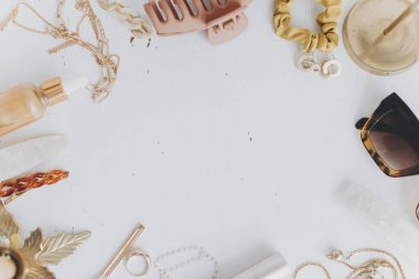 Modern yaz aksesuarları düz ve metin için yeri vardı. Kadınsı ihtiyaçlar. Altın mücevherler, güneş gözlükleri, saç tokaları, tokalar, makyaj malzemeleri beyaz masada klasik mumlarla.