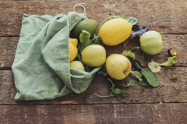 Çevre dostu sıfır atık mutfak. Taze elma, limon, avokado, kırsal ahşap üzerine serpiştirilmiş eko pamuk poşetinden salata yaprakları. Salata malzemeleri. Plastiksiz organik meyve, sebze ve yeşillik
