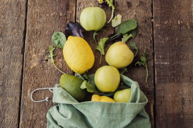 Çevre dostu sıfır atık mutfak. Taze elma, limon, avokado, kırsal ahşap üzerine serpiştirilmiş eko pamuk poşetinden salata yaprakları. Salata malzemeleri. Plastiksiz organik meyve, sebze ve yeşillik