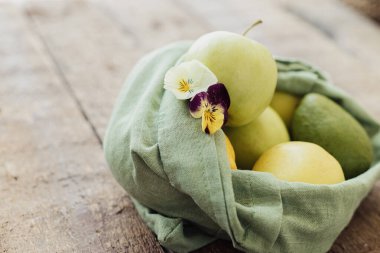 Eko dostu plastik market teslimatı ve alışveriş. Taze elma, avokado, pamuk torbada limon ve kır ağacından yapılmış bir masa. Sıfır kayıp. Organik meyve ve sebzeler yeniden kullanılabilir çantada.
