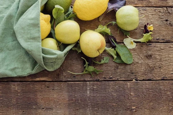 Taze elma, limon, avokado, salata yaprakları kırsal ahşap üzerine serpiştirilmiş eko pamuk torbası, üst manzara, fotokopi alanı. Çevre dostu sıfır atık alışverişi. Plastiksiz organik meyve, sebze, yeşillik