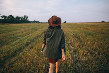Şapkalı, kaygısız, güzel bir kadın yaz tarlasında yürüyor. Genç, mutlu, stil sahibi bir bayan kırsalda dinleniyor, dans ediyor ve akşamın tadını çıkarıyor. Atmosferik an. Arka plan