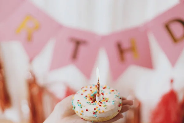Днем Рождения Рука Держит Вкусный Пончик Свечой Фоне Розовой Гирлянды — стоковое фото