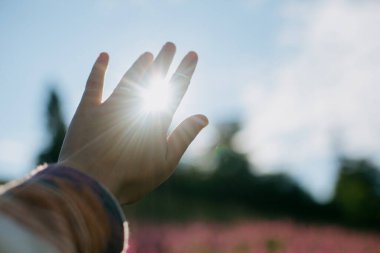 Elin güneşe uzanıyor. Güneşli dağ tepelerinin arka planında güzel bir güneş ışığı var. Dağları gezmek ve keşfetmek. Sabah huzurlu bir an.