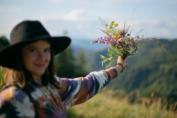 Wanita Pelancong Topi Memegang Karangan Bunga Liar Latar Belakang Bukit — Stok Foto