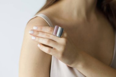 Modern kare pembe yüzüklü ve beyaz manikürlü, zarif, şehvetli bir kadın. Pastel pembe elbiseli, sıra dışı cam aksesuarlı şık bir kadın. Güzellik ve özen.