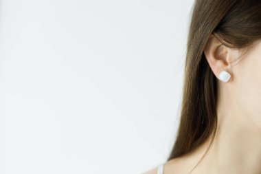 Modern geometrik beyaz küpeli güzel, şehvetli kadın, yakın görüş. Mesaj için yer var. Alışılmadık cam aksesuarları olan şık bir kadın. Güzellik ve bakım konsepti