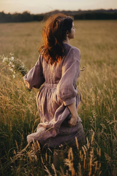 Piękna Kobieta Sukience Biegnąca Dzikimi Kwiatami Ręku Letniej Łące Zachodzie — Zdjęcie stockowe