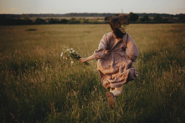 Keten Elbiseli Güzel Bir Kadın Elinde Kır Çiçekleriyle Gün Batımında — Stok fotoğraf
