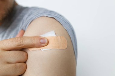 Beyaz arka planda Covid-19 aşısından sonra insan kolunda yapıştırıcı var. Yakın plan. Coronavirus Aşı Kampanyası. Önleme, tedavi ve Covid-19 'dan koruma