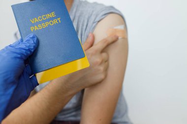 Coronavirus aşısı pasaport konsepti. Coronavirus aşısı aşısı olan bir adamın arkaplanındaki aşı sertifikasını içeren pasaport tutan tıbbi eldiveni teslim edin. Covid-19 'a Seyahat