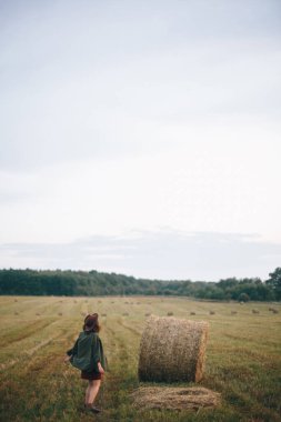 Yaz akşamları saman balyalarında şapkalı güzel bir kadın dans ediyor. Kaygısız mutlu an, kırsalda tatil. Mutlu genç bayan samanlıkta rahatlıyor ve eğleniyor.
