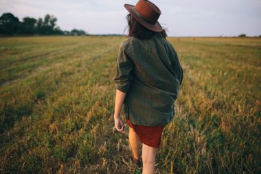 Şapkalı, kaygısız, güzel bir kadın yaz tarlasında yürüyor. Genç, mutlu, stil sahibi bir bayan kırsalda dinleniyor, dans ediyor ve akşamın tadını çıkarıyor. Atmosferik an. Arka plan