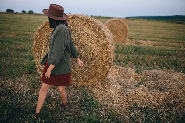 夏夜的田野里 穿着帽子在草袋里跳舞的漂亮的时髦女人 无忧无虑的快乐时光 乡村度假 快乐的年轻女性放松 在干草堆旁玩乐 — 图库照片