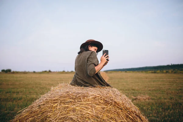 Beautiful Stylish Woman Sitting Haystack Taking Photo Sunset Phone Summer — Stock Photo, Image