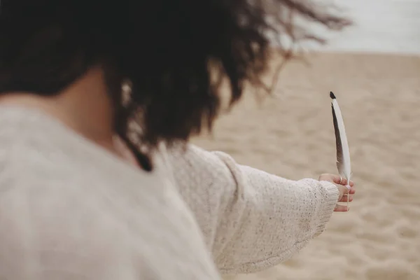 Перо Руке Красивой Женщины Ветреными Волосами Фоне Песчаного Пляжа Моря — стоковое фото