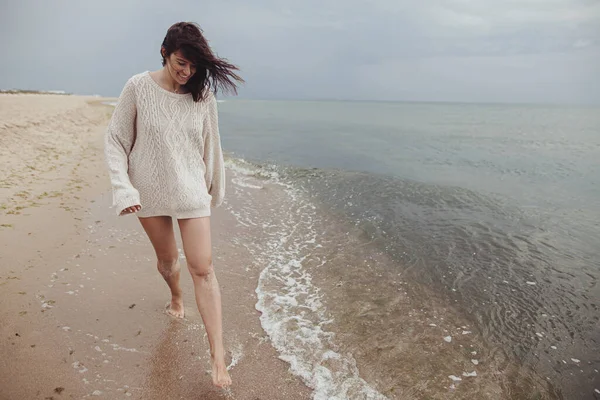Беззаботная Красивая Женщина Трикотажном Свитере Ветреными Волосами Бегает Песчаному Пляжу — стоковое фото