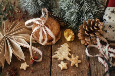 Mutlu Noeller! Noel kurabiyeleri ve sade ahşap masa süsleri. Atmosferik stil Noel kompozisyonu yulaflı kurabiyeler ve xmas hediyeleri. İyi tatiller.