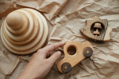 El ele tutuşan modern doğal ahşap araba oyuncağı, piramit, masa üstünde el işi kağıt üzerinde bağlanmış kirpi, üst manzara. Bebek için çevre dostu plastik oyuncaklar. Çocuklar için basit tahta oyuncaklar.