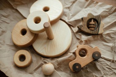 Bebek için çevre dostu plastik oyuncaklar. Modern doğal ahşap piramit, halkalar, bağlayıcı kirpi ve araba ahşap masa üzerinde el işi kağıt üzerinde, üst manzara. Çocuklar için basit tahta oyuncaklar.