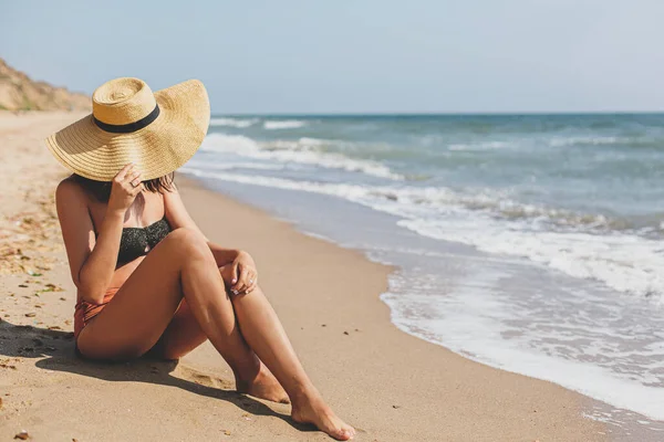 Piękna Stylowa Kobieta Kapeluszu Siedząca Piaszczystej Plaży Falach Morskich Opalająca — Zdjęcie stockowe