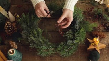 Noel çelengi yapıyorum. Kadın ellerinin köknar ağacı ve kırmızı böğürtlenlerle Noel çelengi yaptığı kır ağacından yapılmış mumlar ve çam kozalakları. Tatilin gelişi. Mutlu Noeller.