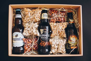 Lviv, Ukrayna - 1 Aralık 2017: Hoegaarden, Grimbergen ve Guinness bira şişeleri etiketli ve hediye kutusunda saman üzerinde tuzlanmış fındık atıştırmalıkları. Erkek doğum günü için şık bir hediye kutusu, babalar günü. Üst görünüm