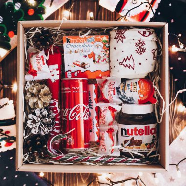 Lviv, Ukrayna - 1 Aralık 2017: Coca Cola kutusu, şık çoraplar, kitkat, daha nazik çikolata, noel ışıklarıyla samanlıkta fındık ezmesi. Üst Manzara. Noel için hediye kutusu, doğum günü, babalar günü