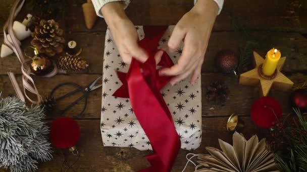 Handen Omwikkelen Stijlvolle Kerstcadeau Met Rood Lint Rustieke Houten Tafel — Stockvideo