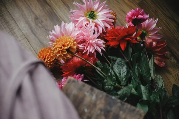 素朴な部屋で木製の床に秋の花花束 上記のビュー 美しいカラフルなダリアを配置リネンドレスの女性 田舎の秋のシーズン 農村部のスローライフ 花屋さん — ストック写真