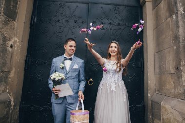 Mutlu gelin ve damat kutsal evlilikten sonra kilisenin arka planına şeker atıyor. Katedralde düğün töreni. Tatlı ile güzel duygusal evlilik çifti