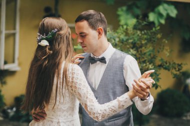 Gelin ve damat şık bir restoranda ağaçların arasında nazikçe dans ediyorlar. Provence düğünü. Güzel romantik bir çift ilk dansı yapıyor. Provence düğün resepsiyonu