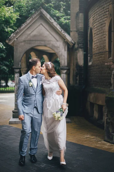 美しい感情的な結婚式のカップルのキスやヨーロッパの街を歩く プロバンス結婚式 日当たりの良い通りで教会の背景を歩くスタイリッシュな幸せな花嫁と新郎 — ストック写真