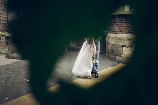 雨の中 古い教会を背景に傘の下でキスをするスタイリッシュな花嫁と新郎は 木の葉を通して創造的なビュー プロバンス結婚式 傘の下で抱擁美しい結婚式のカップル — ストック写真