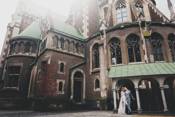 日当たりの良い通りにある古い教会を背景にしたスタイリッシュな花嫁と新郎 ロマンチックな瞬間だ プロバンス結婚式 美しいです官能的な結婚式カップル優しく抱擁でヨーロッパの都市 — ストック写真