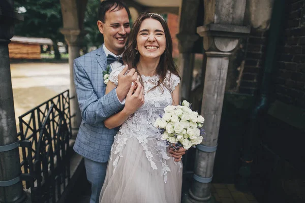 在欧洲的城市里 美丽的情爱的新婚夫妇笑着拥抱在一起 普罗旺斯婚礼时尚快乐的新娘和新郎笑着拥抱在古老教堂的背景下 — 图库照片