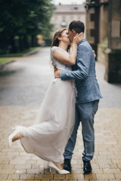 雨の中で古い教会の背景にスタイリッシュな官能的な花嫁と新郎キスのぼやけたイメージ プロバンス結婚式 美しい感情的な結婚式のカップルを受け入れる ロマンチックな瞬間 — ストック写真