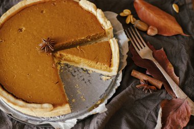 Kağıt üzerinde parşömen kâğıdı üzerinde balkabağı turtası keten peçete, sonbahar yaprakları, anason, tarçın ve çatal bıçaklı. Mutlu Şükran Günleri Ev yapımı kabak tartı tarifi.