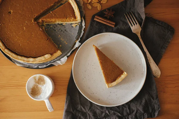 Modern tabakta balkabağı dilimi ve kırsal masada keten peçete, anason ve tarçınlı sıcak kahve. Ev yapımı kabaklı tart tarifi. Üst Manzara. Mutlu Şükran Günleri