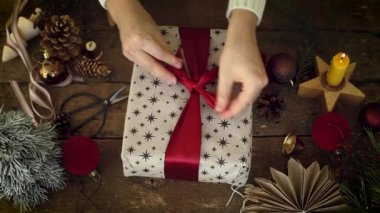 Kadın ellerinin üst görüntüsü Noel hediyesi kutusuna fiyonk bağlar