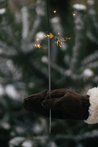 新年快乐 傍晚时分 妇女们在雪地里的松树枝干上手握时髦的手套 点燃着炽热的焰火 手握着燃烧的火花 大气魔法时刻 假期快乐 — 图库照片
