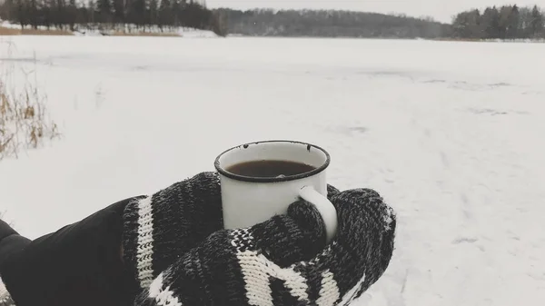 冬日里 手握舒适的手套 在雪湖的背景下 端着一杯热茶 在寒冷的冬季远足和旅行 文字空间 游手好闲 — 图库照片