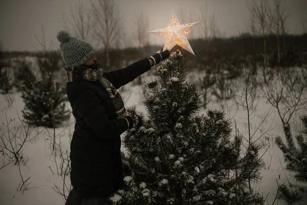 Žena Zdobí Borovice Zářící Velkou Vánoční Hvězdou Zasněženém Zimním Parku — Stock fotografie