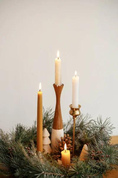 现代节日期间 在白色墙壁的背景下 木制桌子上挂着用蜡烛和松树装饰的时尚圣诞花环 大气冬季时间 假日的到来 — 图库照片