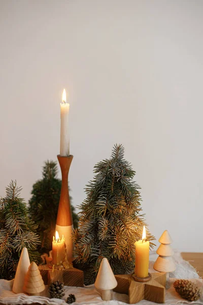 现代鸟类节日期间 在白色墙壁的背景下 木制桌子上挂着时尚的圣诞蜡烛和松树装饰 大气冬季时间 假日的到来 — 图库照片