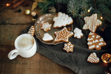 Noel kurabiyeleri, şık beyaz bardakta kahve, köknar dalları, peçetedeki sıcak ışıklar ve kırsal ahşap masa. Keyifsiz bir görüntü. Kış zamanı. İyi tatiller.!