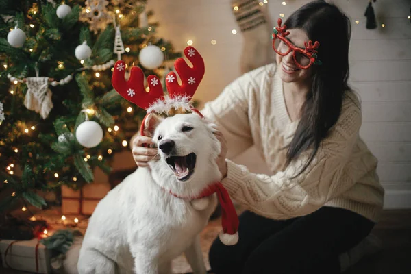 Стильная Счастливая Женщина Играющая Восхитительной Собакой Оленьих Рогах Елкой Огнях — стоковое фото