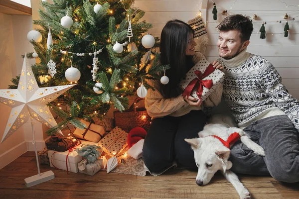 Стильная Счастливая Пара Милой Собакой Обменивающейся Рождественским Подарком Красным Бантом — стоковое фото