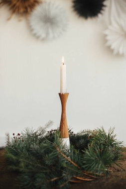 Kırsal Noel çelenginde yanan mum yakmak ahşap masanın üzerinde duvardaki isviçreli kağıt yıldızlarının arka planında. Noel yaklaşıyor. Karamsar atmosfer zamanı. Mutlu Noeller ve mutlu tatiller!